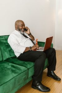 trusts in estate planning, image of a corpulent man wearing a tie talking on the phone while using a laptop